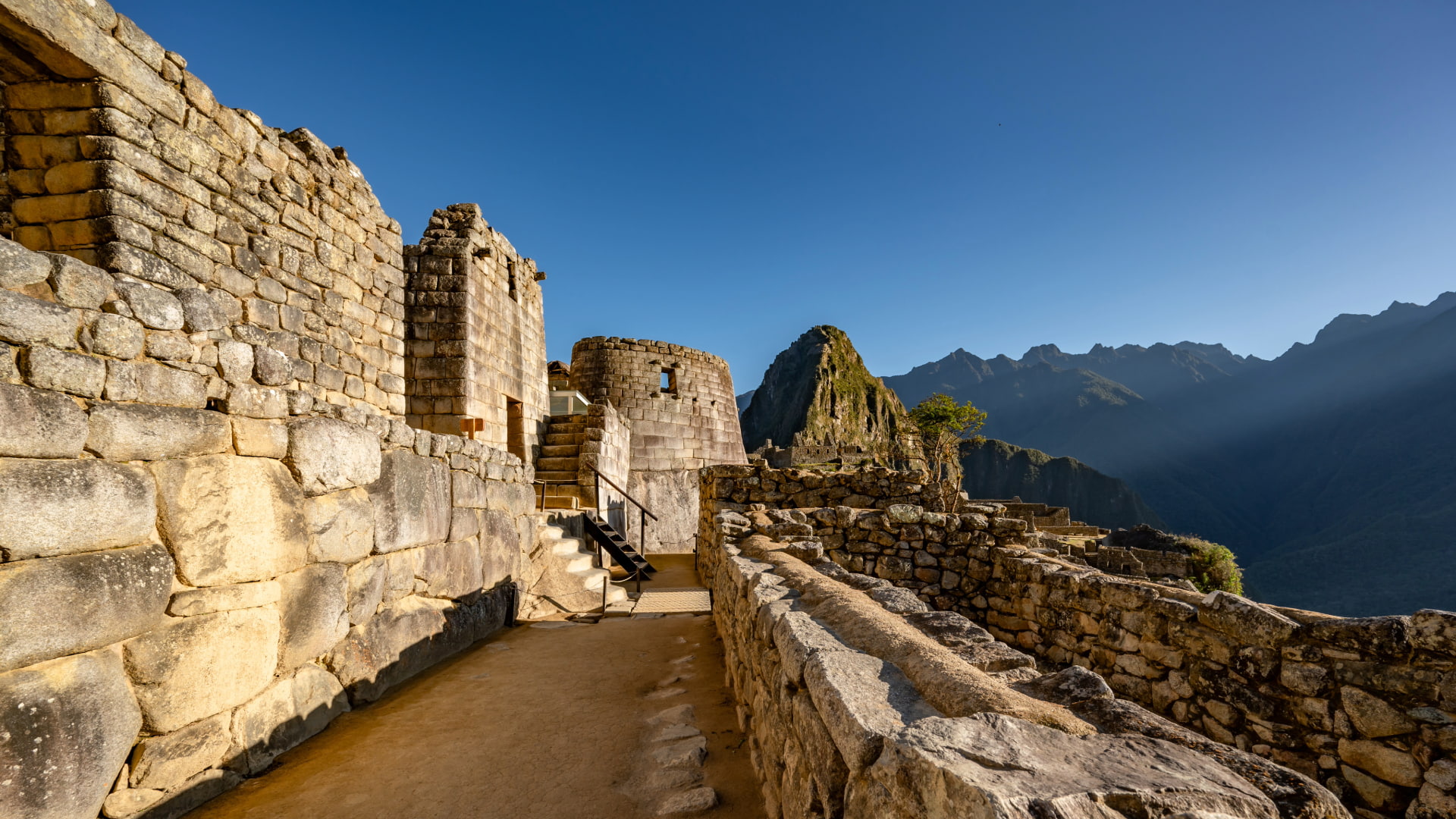 Ancient stone path of the Classic Inca Trail 4 Days winding through green mountains, representing the Inca Trail Hike - Aremika Travel