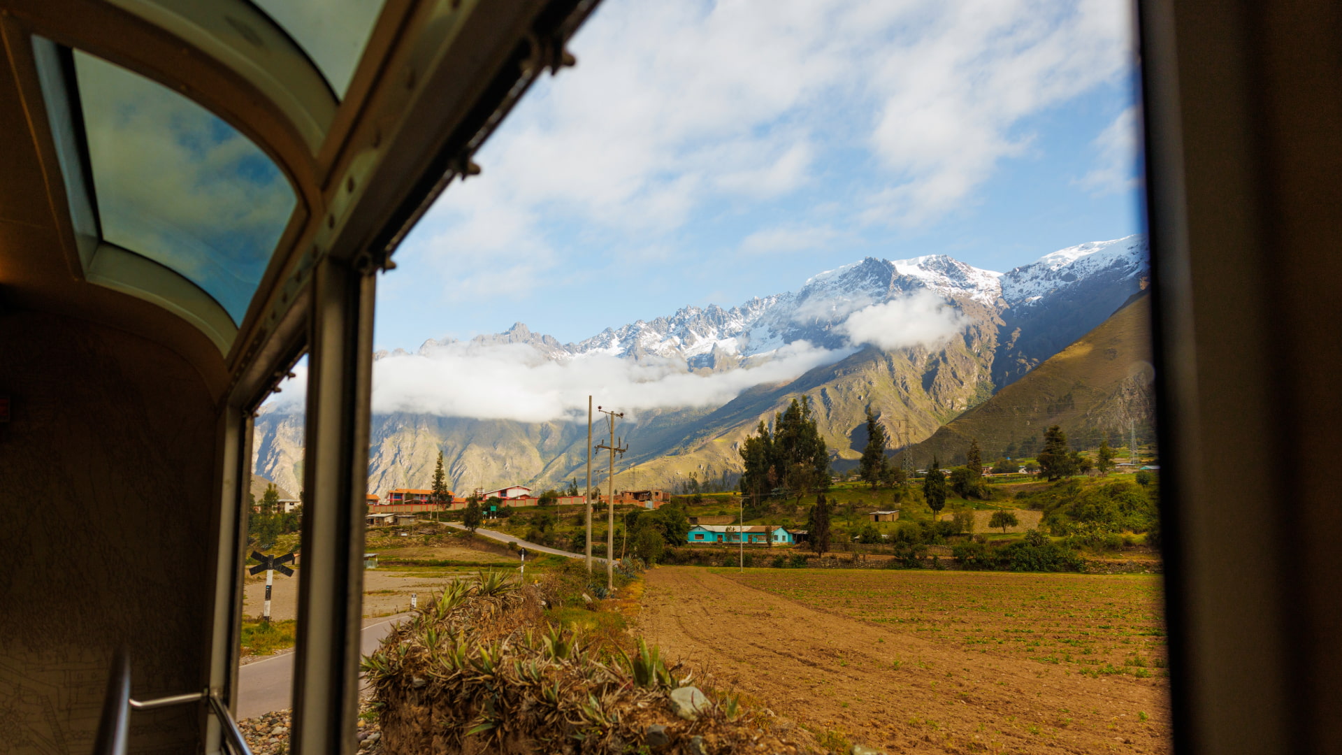Panoramic view of snow-capped mountains and a valley from an observation car window during a 1 Day Luxury Tour to Machu Picchu - Aremika Travel