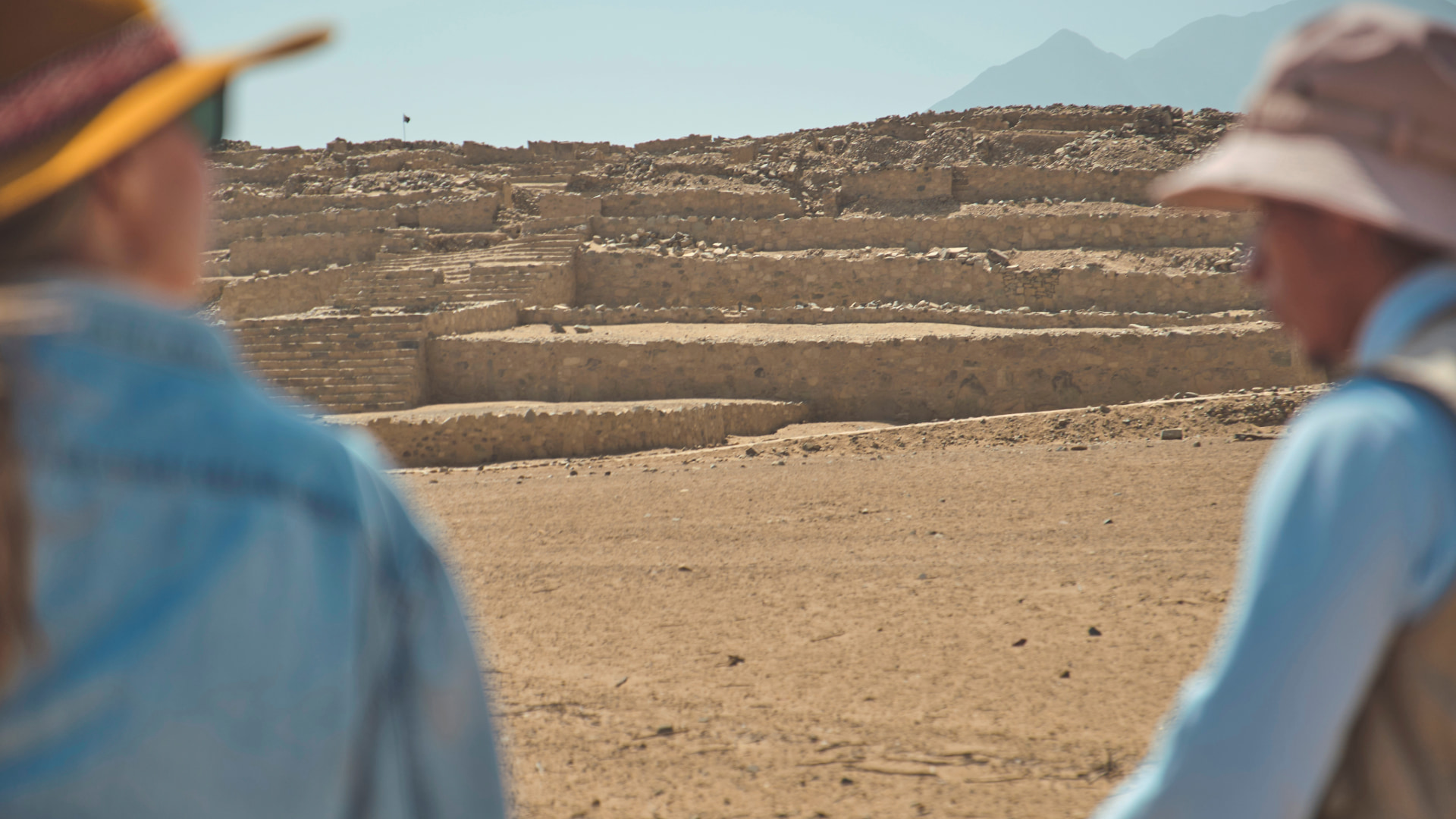 Two travelers on the Tour to Caral from Lima look together at the ancient pyramids of the oldest city in the Americas - Aremika Travel